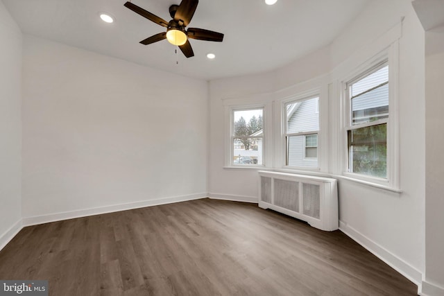 empty room featuring hardwood / wood-style floors, radiator, and ceiling fan