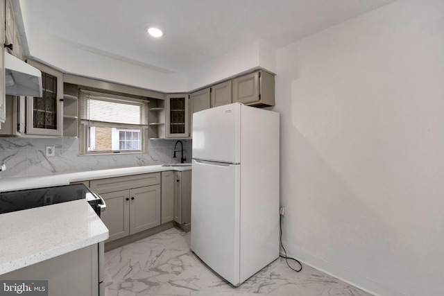 kitchen with decorative backsplash, white refrigerator, gray cabinetry, and sink