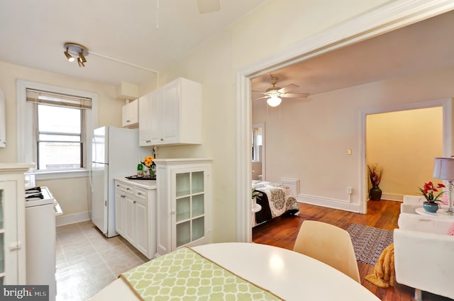 kitchen with white cabinets, light wood-type flooring, white refrigerator, and ceiling fan