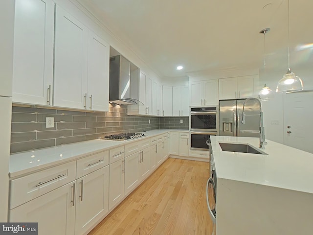 kitchen with sink, white cabinets, wall chimney exhaust hood, and appliances with stainless steel finishes