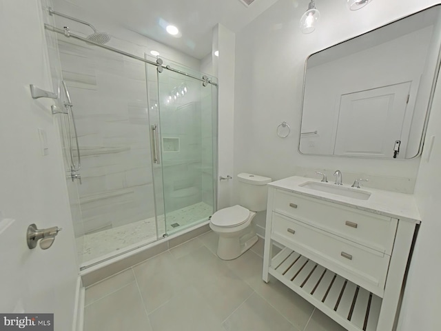 bathroom with tile patterned flooring, vanity, a shower with shower door, and toilet