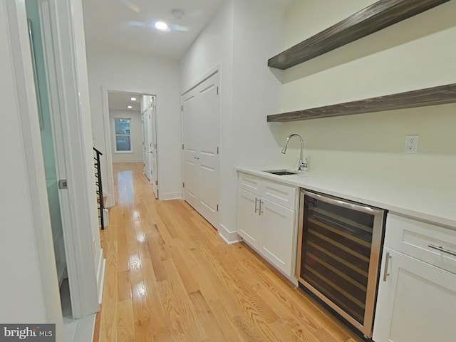 bar featuring white cabinetry, sink, beverage cooler, and light hardwood / wood-style floors