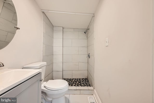 bathroom with a tile shower, vanity, and toilet