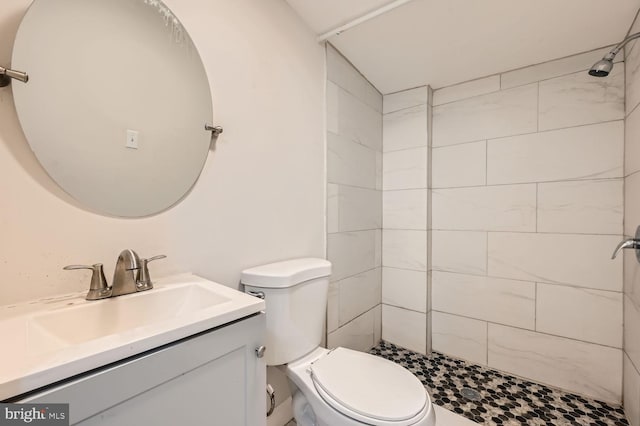 bathroom with vanity, toilet, and a tile shower