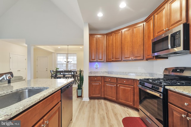 kitchen featuring light stone countertops, sink, light hardwood / wood-style flooring, vaulted ceiling, and appliances with stainless steel finishes