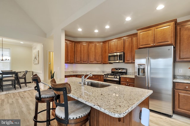 kitchen with appliances with stainless steel finishes, sink, a center island with sink, light hardwood / wood-style flooring, and lofted ceiling