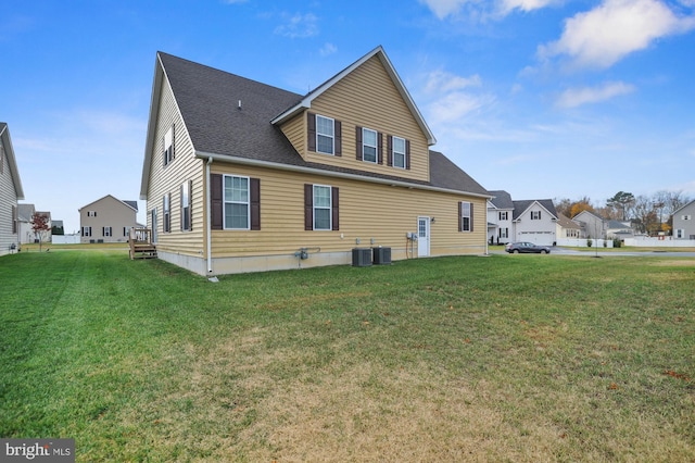 rear view of property featuring a lawn and central AC