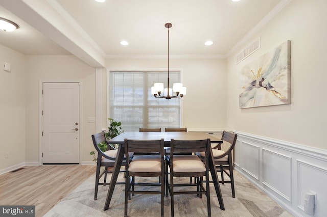 dining space featuring light hardwood / wood-style floors, crown molding, and an inviting chandelier