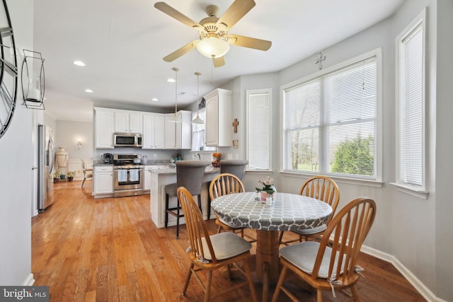 dining space featuring ceiling fan, light wood-type flooring, and sink