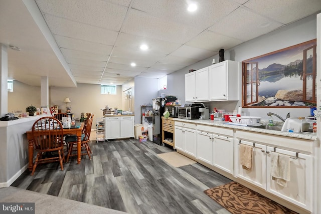 kitchen with a paneled ceiling, dark hardwood / wood-style flooring, white cabinetry, and sink