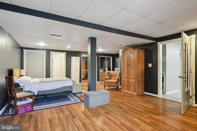 bedroom with wood-type flooring and a paneled ceiling