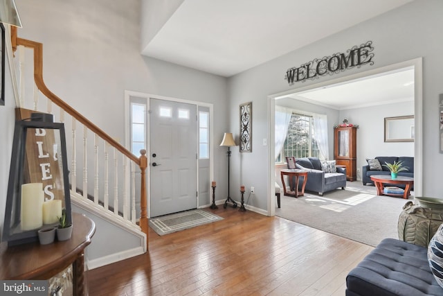 foyer entrance with crown molding and hardwood / wood-style floors