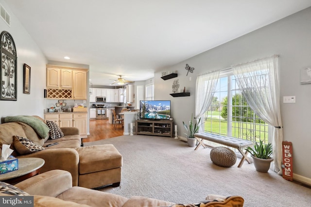 carpeted living room with ceiling fan