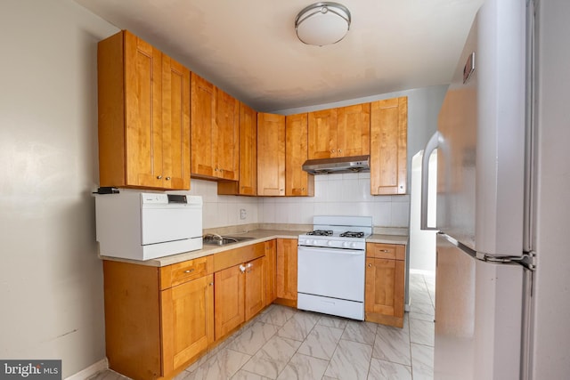 kitchen featuring decorative backsplash, white appliances, and sink