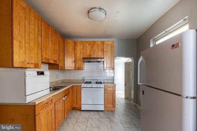 kitchen featuring backsplash, sink, and white appliances