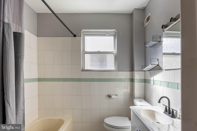 full bathroom with vanity, toilet, tile walls, and shower / tub combo