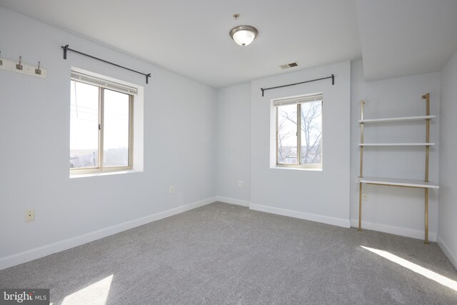 carpeted spare room featuring visible vents and baseboards