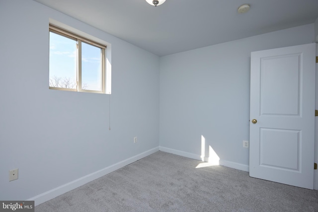 unfurnished room featuring light carpet and baseboards