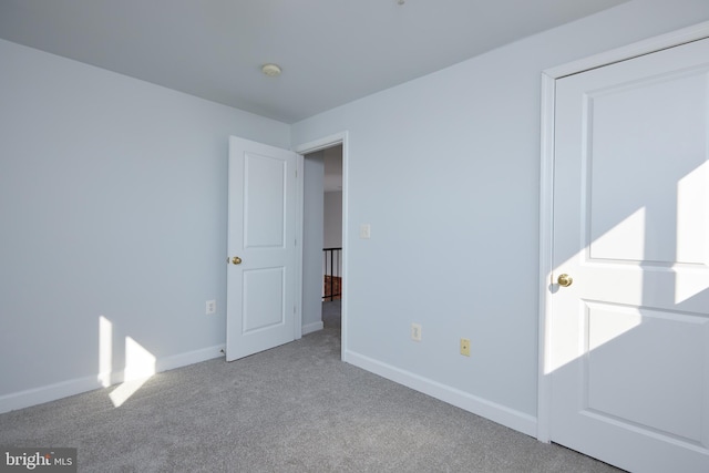 unfurnished bedroom featuring light carpet and baseboards