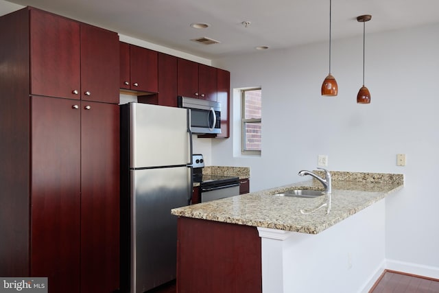 kitchen with pendant lighting, stainless steel appliances, visible vents, a sink, and a peninsula