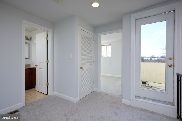 hallway featuring baseboards, recessed lighting, visible vents, and light colored carpet