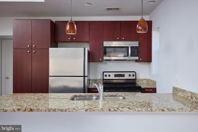 kitchen featuring stainless steel appliances, visible vents, a sink, and hanging light fixtures