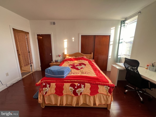 bedroom with dark hardwood / wood-style floors and a closet