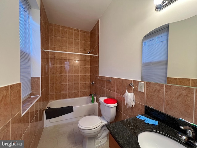 full bathroom with tile patterned flooring, tiled shower / bath, toilet, and tile walls