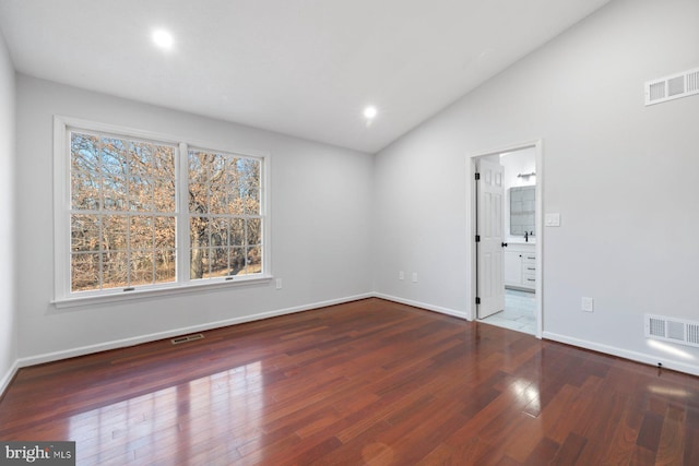 spare room featuring dark hardwood / wood-style flooring and lofted ceiling