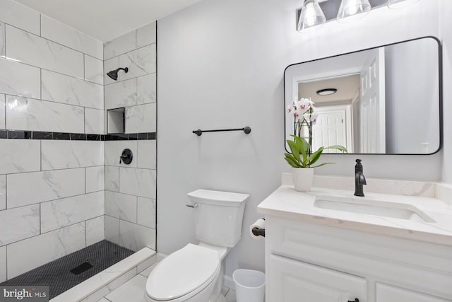 bathroom featuring toilet, vanity, and tiled shower