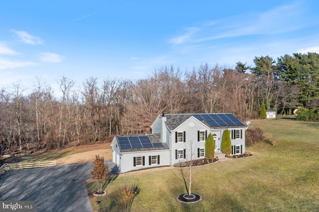 view of front of home featuring solar panels and a front lawn