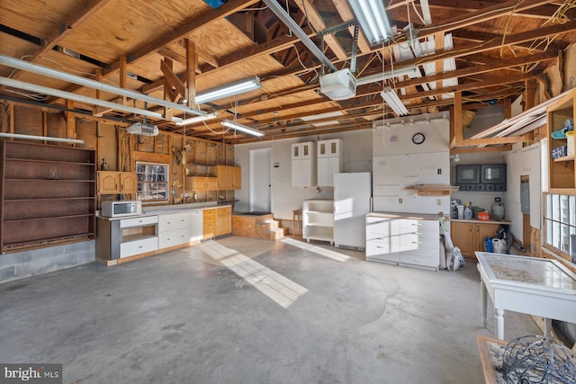 garage featuring a workshop area, white fridge, and a garage door opener