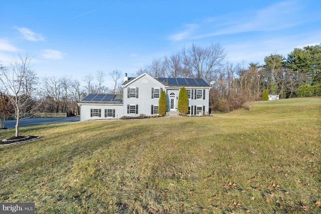 view of front of property featuring a front yard and solar panels