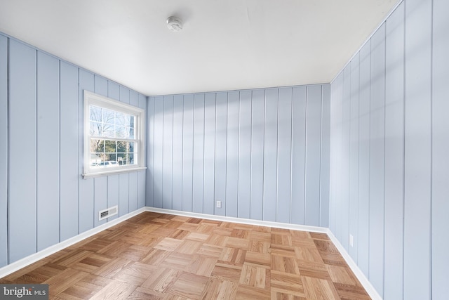 empty room with wood walls and light parquet flooring