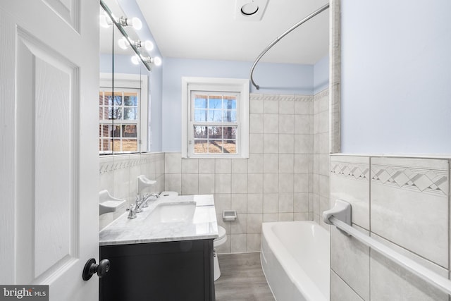 full bathroom with vanity, hardwood / wood-style flooring, toilet, tile walls, and shower / bath combination