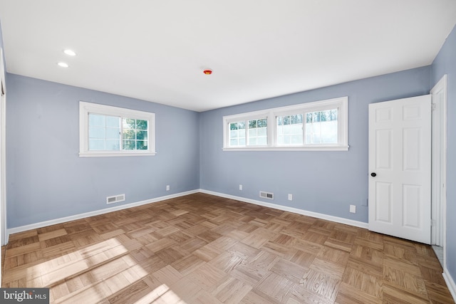 spare room with a wealth of natural light and light parquet flooring