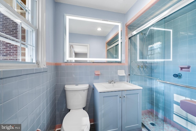 bathroom with toilet, vanity, tile walls, and walk in shower