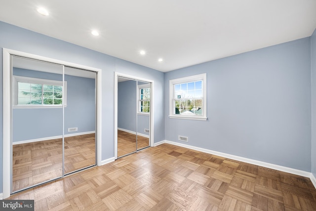 unfurnished bedroom featuring multiple closets and light parquet floors