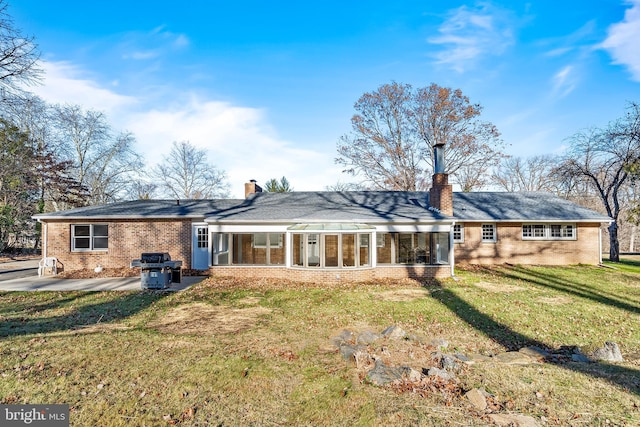 back of property with a patio area, a sunroom, and a yard