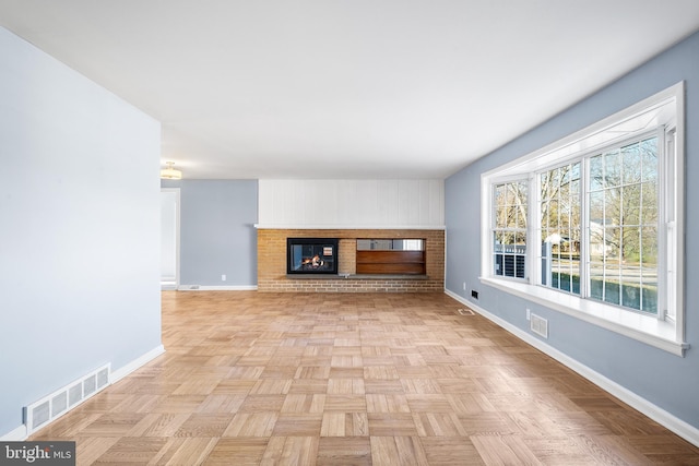 unfurnished living room with a brick fireplace and light parquet floors