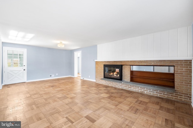 unfurnished living room featuring a fireplace and light parquet flooring