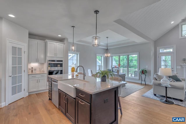 kitchen with light stone countertops, sink, white cabinets, and light hardwood / wood-style floors