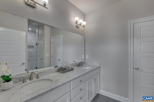 bathroom with tile patterned flooring, a tile shower, and vanity