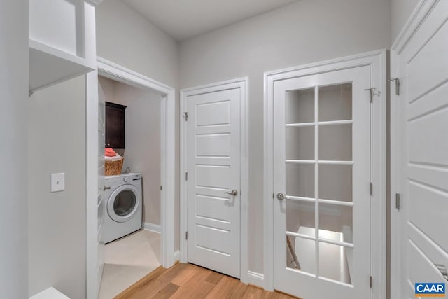 clothes washing area featuring washer / clothes dryer, light hardwood / wood-style flooring, and cabinets