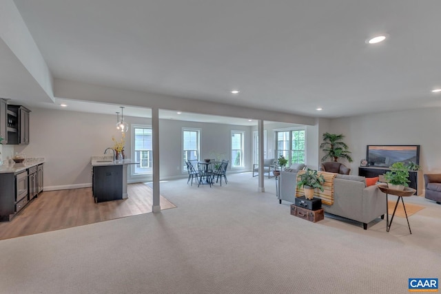 living room with light colored carpet, a healthy amount of sunlight, and sink