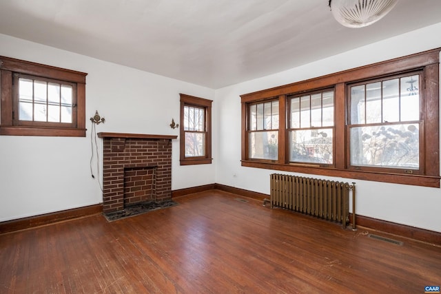 unfurnished living room featuring plenty of natural light, dark hardwood / wood-style floors, and radiator heating unit