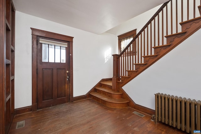 foyer entrance with radiator and dark hardwood / wood-style floors