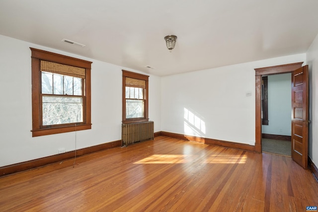 spare room featuring radiator heating unit and hardwood / wood-style floors