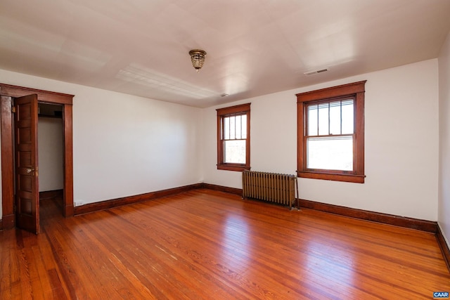 spare room with wood-type flooring and radiator heating unit