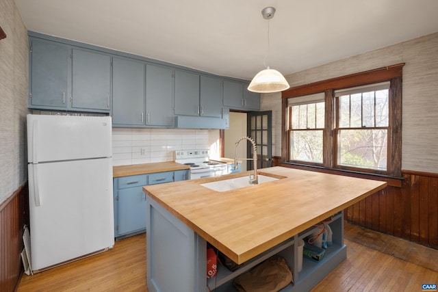 kitchen featuring pendant lighting, white appliances, wooden counters, sink, and light wood-type flooring